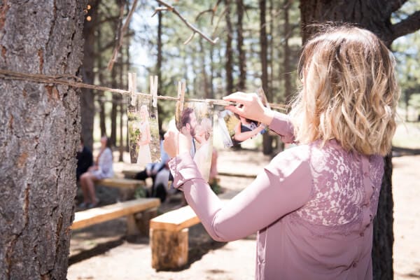 Clotheslines with engagement pictures for a special touch at an outdoor woodland themed wedding.