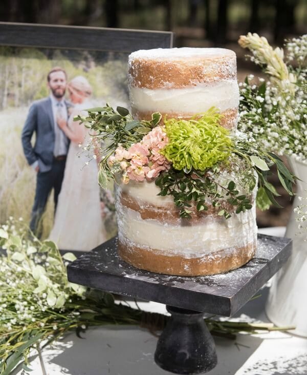 Simple and elegant wedding cake for an outdoor woodland themed wedding. Love the blush colored flowers and babies breath. The raw look of the cake is so cool!