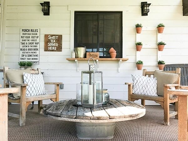 Love the teak chairs, lanterns and wire spool coffee table in this farmhouse summer porch decor!