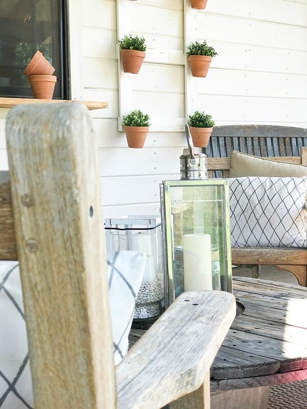 Salvaged furniture, farmhouse wall planters, and unique lanterns create a lovely farmhouse summer porch!