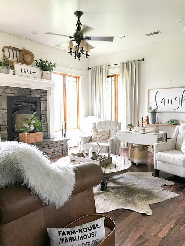 Farmhouse living room summer decor complete with large farmhouse signs, pottery, rustic wood, and fresh lilac cuttings. A touch of navy blue accents finishes off the space.