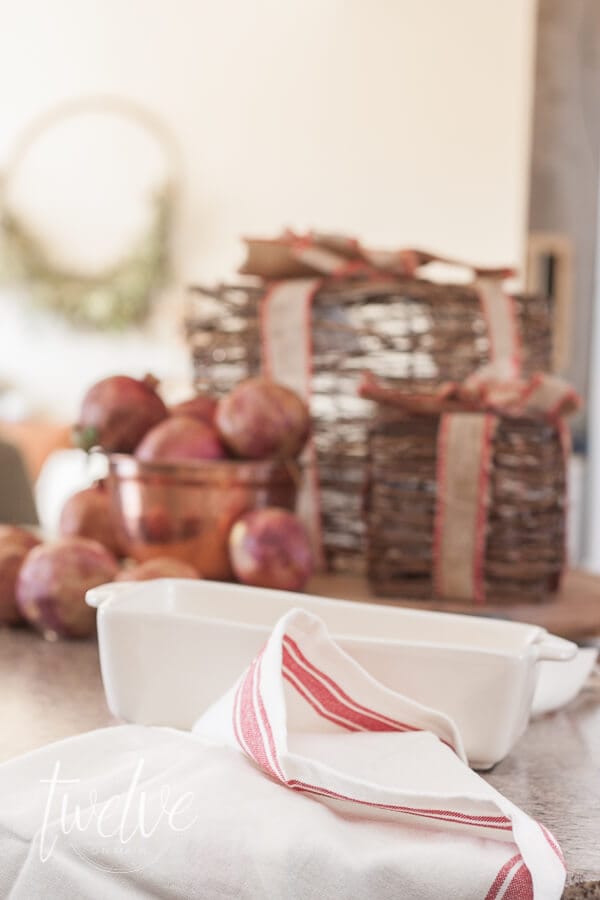 Faux gifts, pomegranates, and red grainsack towels for this farmhouse Christmas kitchen.