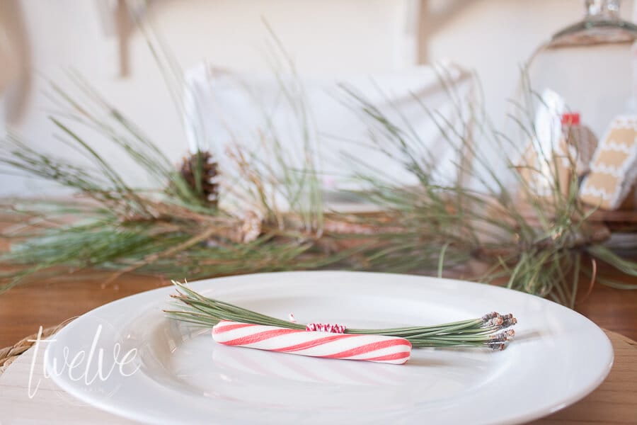 Create a classic red and white farmhouse Christmas tablescape with mini gingerbread houses, red ticking stripe fabric, and nature inspired elements.