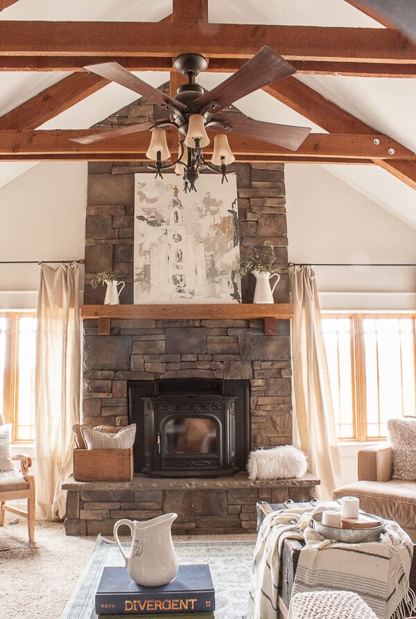Farmhouse art ona stacked stone fireplace, exposed beams, dropcloth curtains, and cozy ticking stripe throw pillows and blankets create the perfect mood for anyone looking to just relax for a bit.
