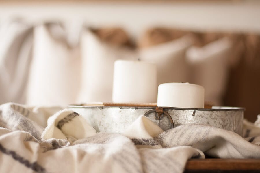 I love combining different textures when decoratiing my farmhouse living room. Love the look of a cozy throw blanket, a galvanized tray, and some simple white candles. 