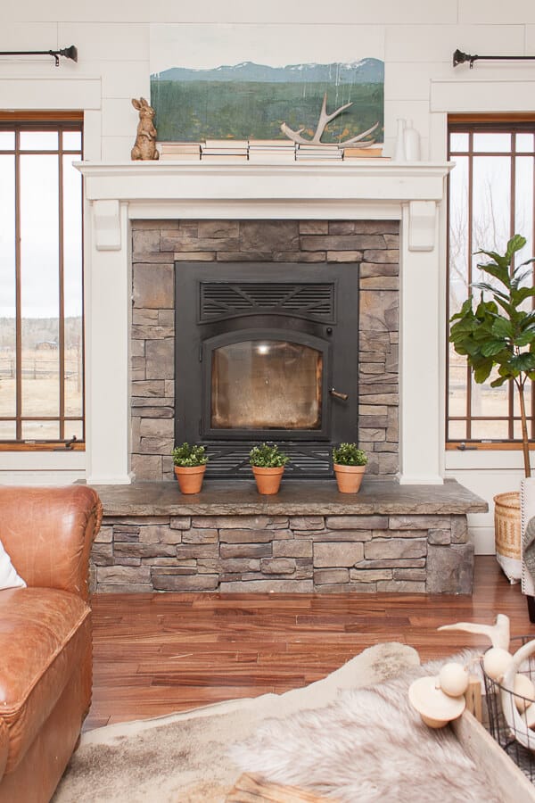 Farmhouse spring decor on this stacked stone fireplace and mantel. Gorgeous custom artwork!