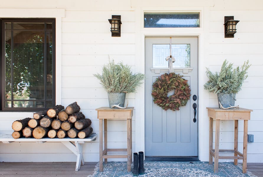 Farmhouse fall decor eith firewood, zinc buckets, and large rug, and magnolia wreath!