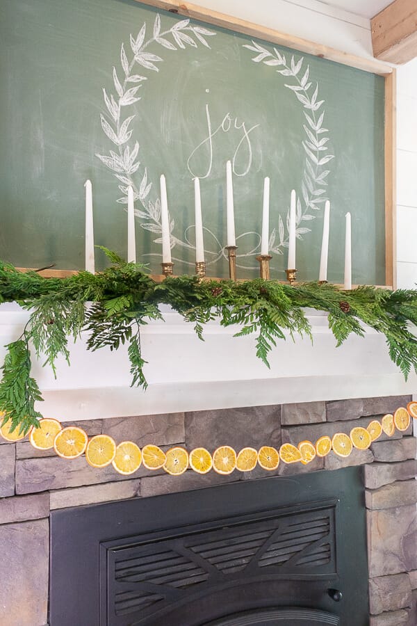 Scandinavian Christmas mantel with dried orange garland, fresh greenery, and amazing vintage Baldwin brass candlesticks!