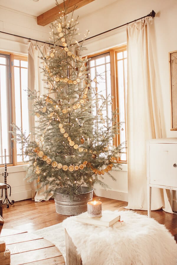 Scandinavian style Christmas tree with dried orange garland, copper twinkle lights, and some simple metallic ornaments.