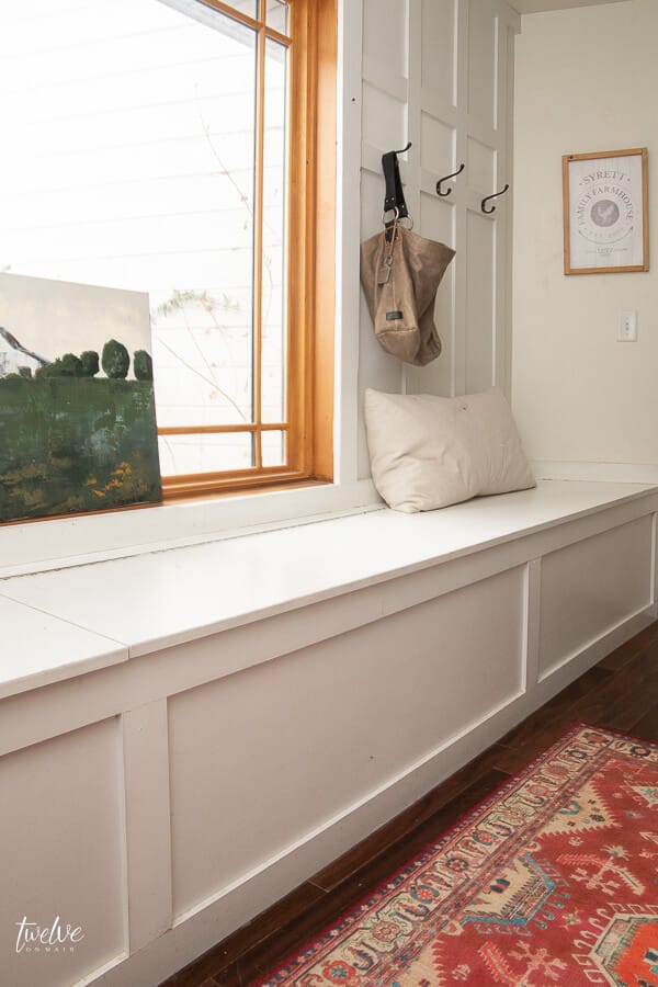 Farmhouse style white mudroom complete with gorgeous custom artwork and colorful vintage rug.