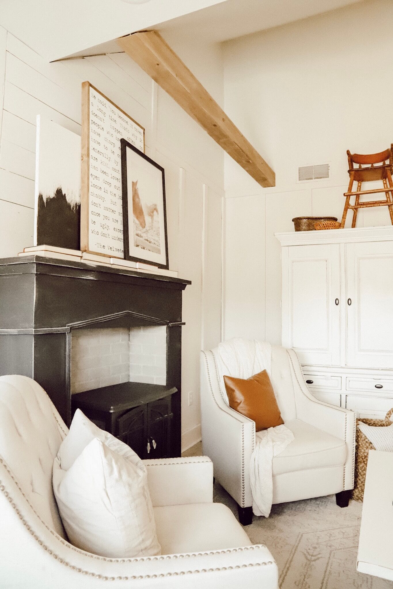 This space is amazing! Love the white along the striking painted fireplace in black, the wood beams and the horse art!