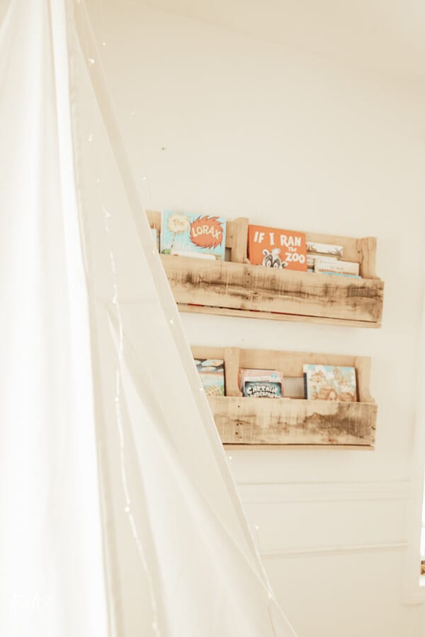 Pallet bookshelves hold our daughters books in her cozy boho style reading nook.