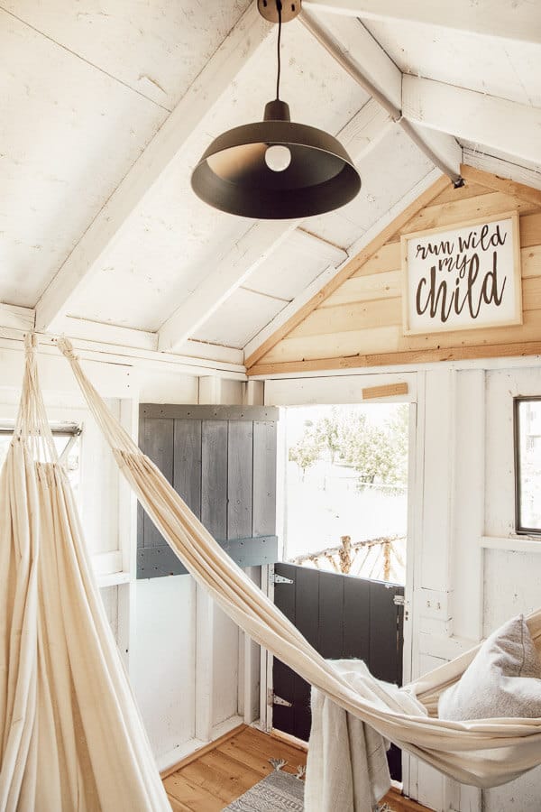 Check out this amazing farmhouse style treehouse design! Gorgeous details, hammocks, a front porch, lights and more!