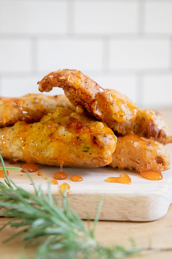 The crispiest fried chicken recipe ever! It has a flavorful herb infused batter and its topped off with a honey Sriracha sauce that is sweet and spicy!