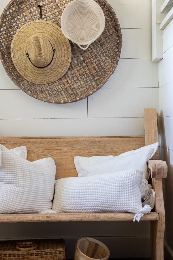 Fall decor ideas including my wooden church pew in the entry with baskets on the wall, topped with straw hats and rope baskets.  White pillows top of the vintage church pew and a basket of pears adds a touch of color to this neutral fall entryway.  