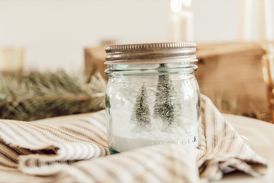 Love these mason jar Christmas tree scenes on this gorgeous Christmas tablescape with candles.