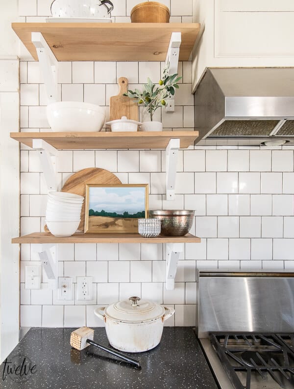 Open shelves in the kitchen with cutting boards, gorgeous white dishes, copper bowls, and custom landscape art that you can get yourself! This landscape art is available for FREE, click here to get your own FREE printable art!