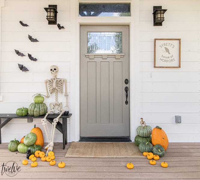 Affordable Halloween porch ideas including paper bats, real pumpkins, and a spooky posable skeleton!