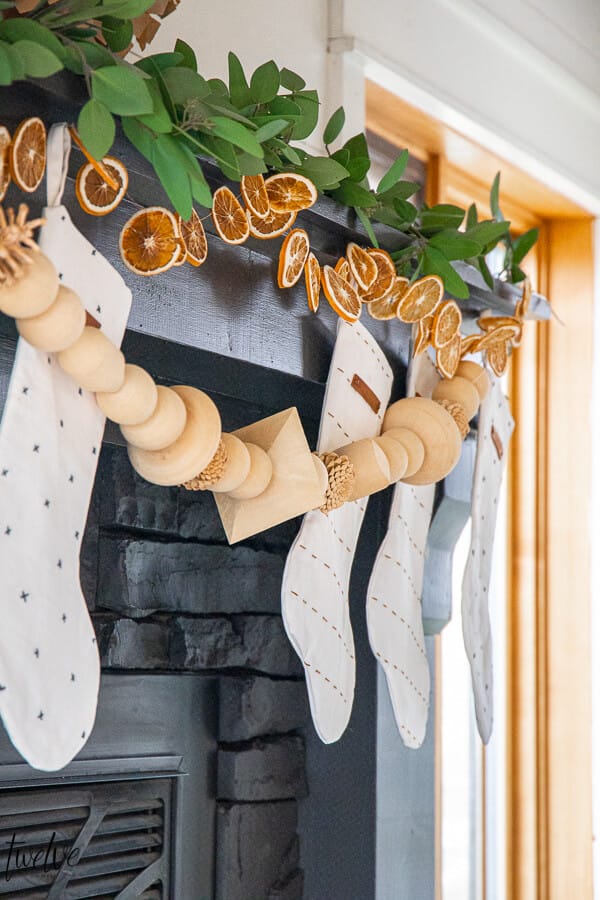 Gorgeous boho/Scandinavian holiday mantel complete with eucalyptus, dried orange slices, and wooden bead garland.