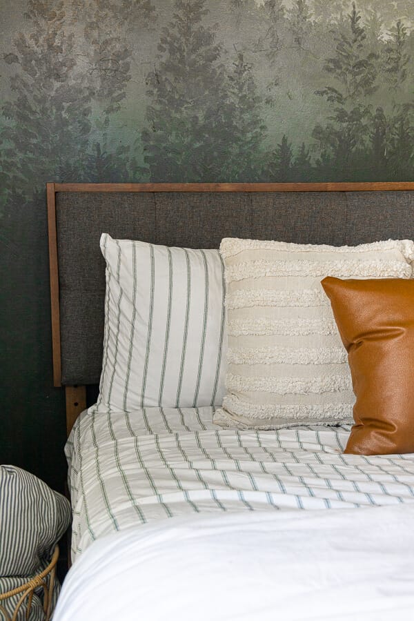 Gorgeous guest bedroom complete with a cozy bed, beautifully painted custom forest wall mural, cozy seating, and so much more. 