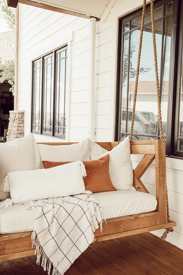 Simple fall front porch decor using items that will bring you from the summer to fall without spending a lot of money! This gorgeous porch swing with fall touches looks so inviting!