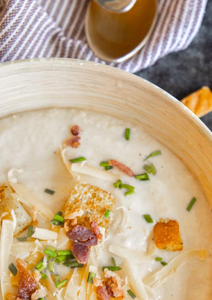 This cauliflower and cheddar soup is an easy weeknight meal. This is a creamy, flavorful soup with cauliflower, sharp cheddar and cream.  This is an easy soup recipe that is great any time of year. This cauliflower cheese soup is a hit for both adults and kids. It is a great way to sneak those veggies in! Top it with chives and bacon, and use a slice of fresh sourdough bread to mop up this creamy soup.