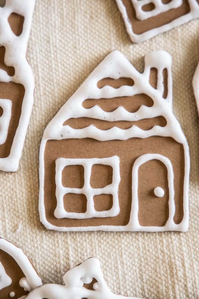 Make these easy gingerbread house ornaments using craft or chipboard, a Cricut Machine, homemade puff paint and more!