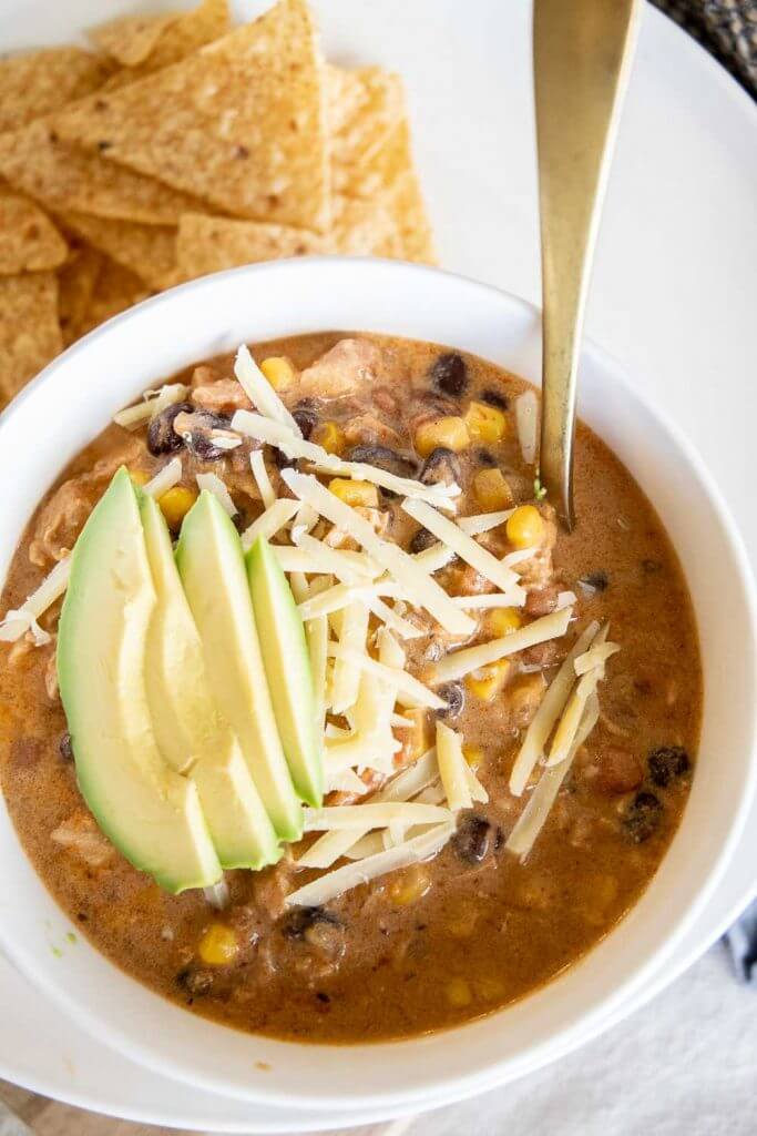 Easy to make creamy tortilla soup with chicken, beans, corn and more. Can be made in  the crock pot or on the stovetop! It is so flavorful!